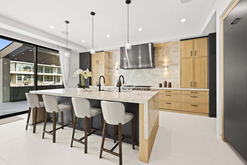 Kitchen with waterfall stone island, oak cabinetry and pendant lighting